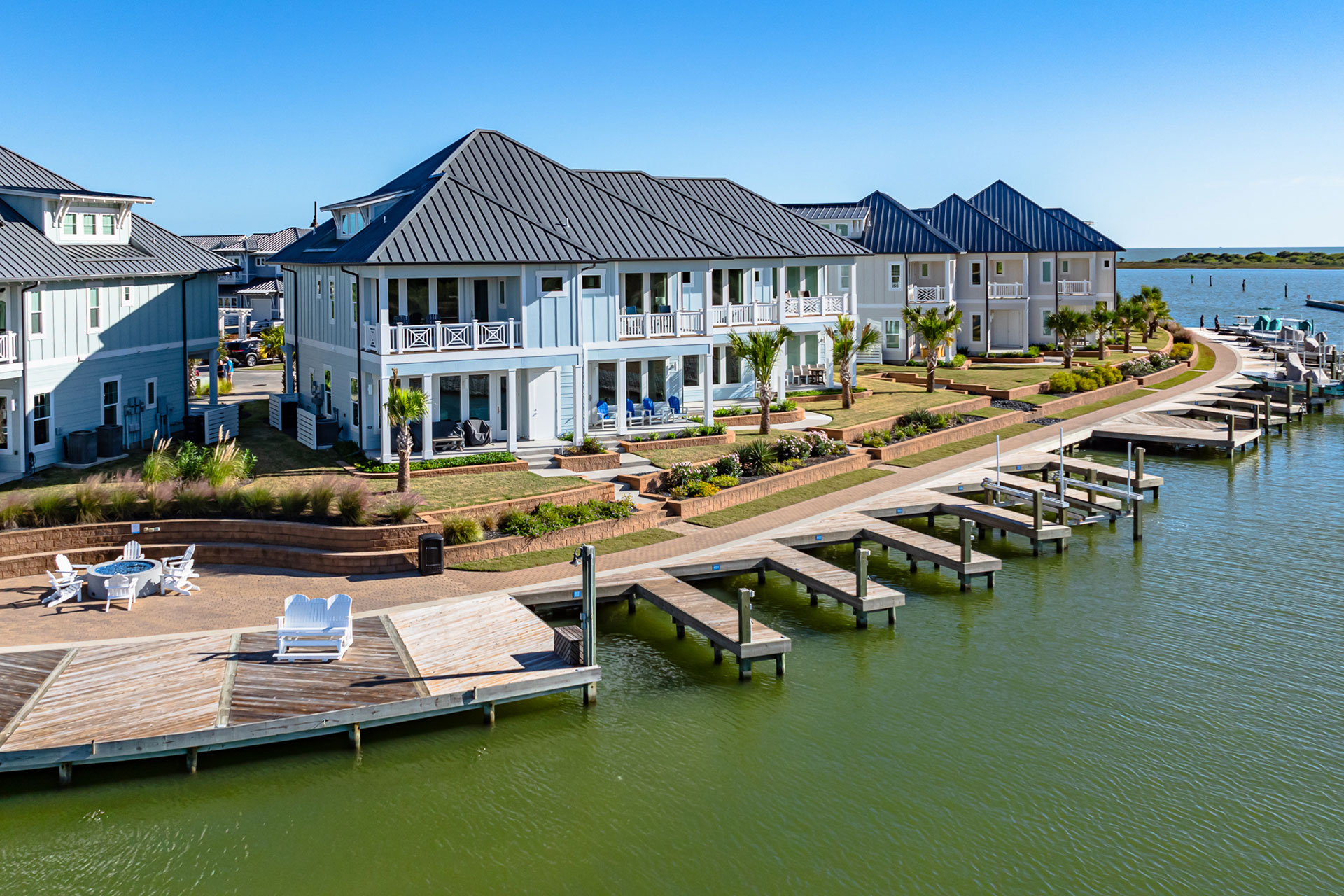 Light blue waterfront townhomes with private boat docks and coastal landscaping