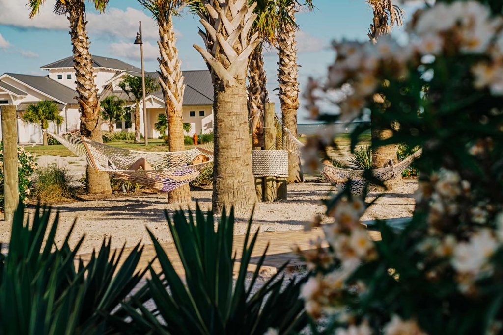 Woman relaxing in a rope hammock between palm trees at a coastal resort.