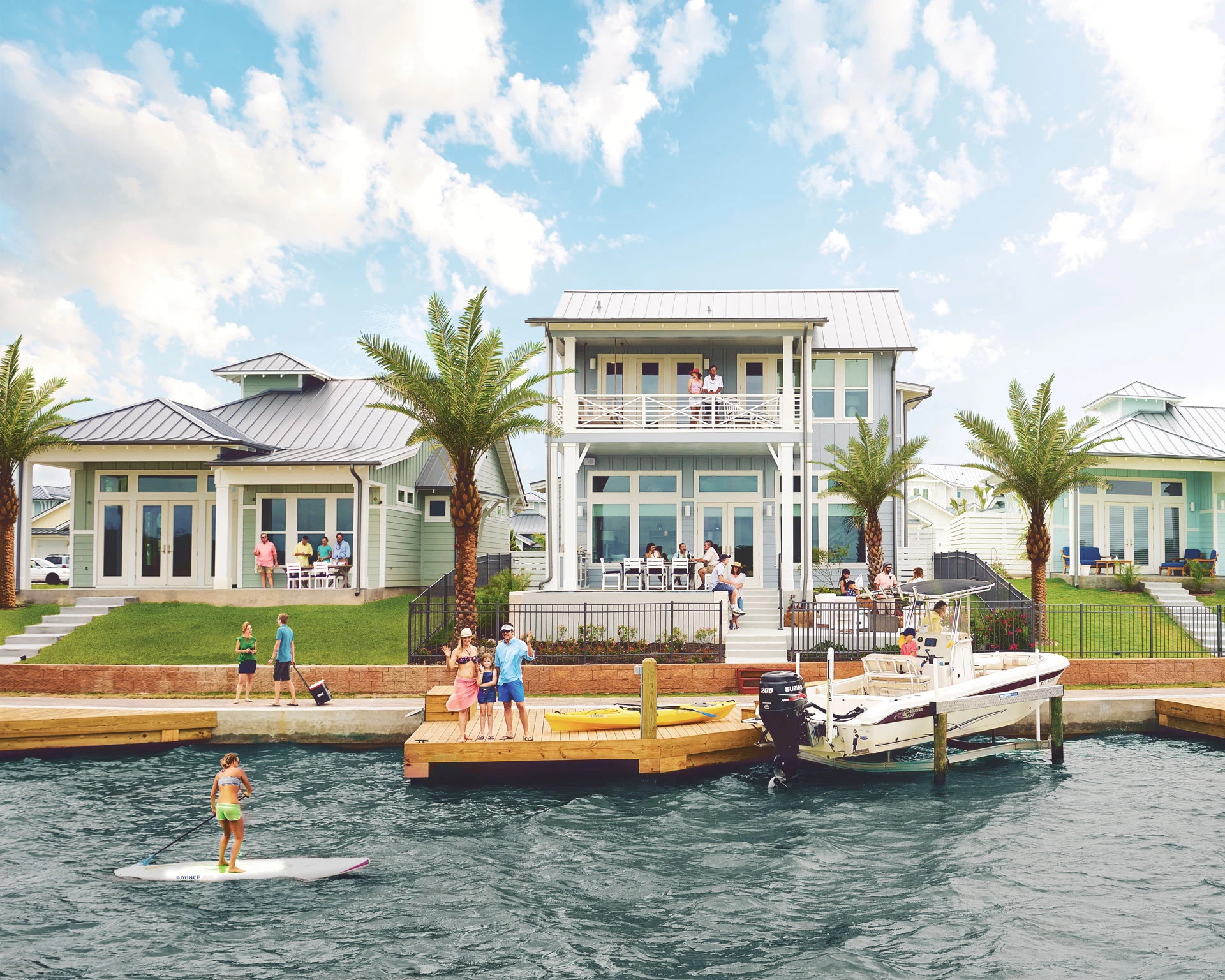 Luxury waterfront houses with private docks, a motorboat, and people paddleboarding.