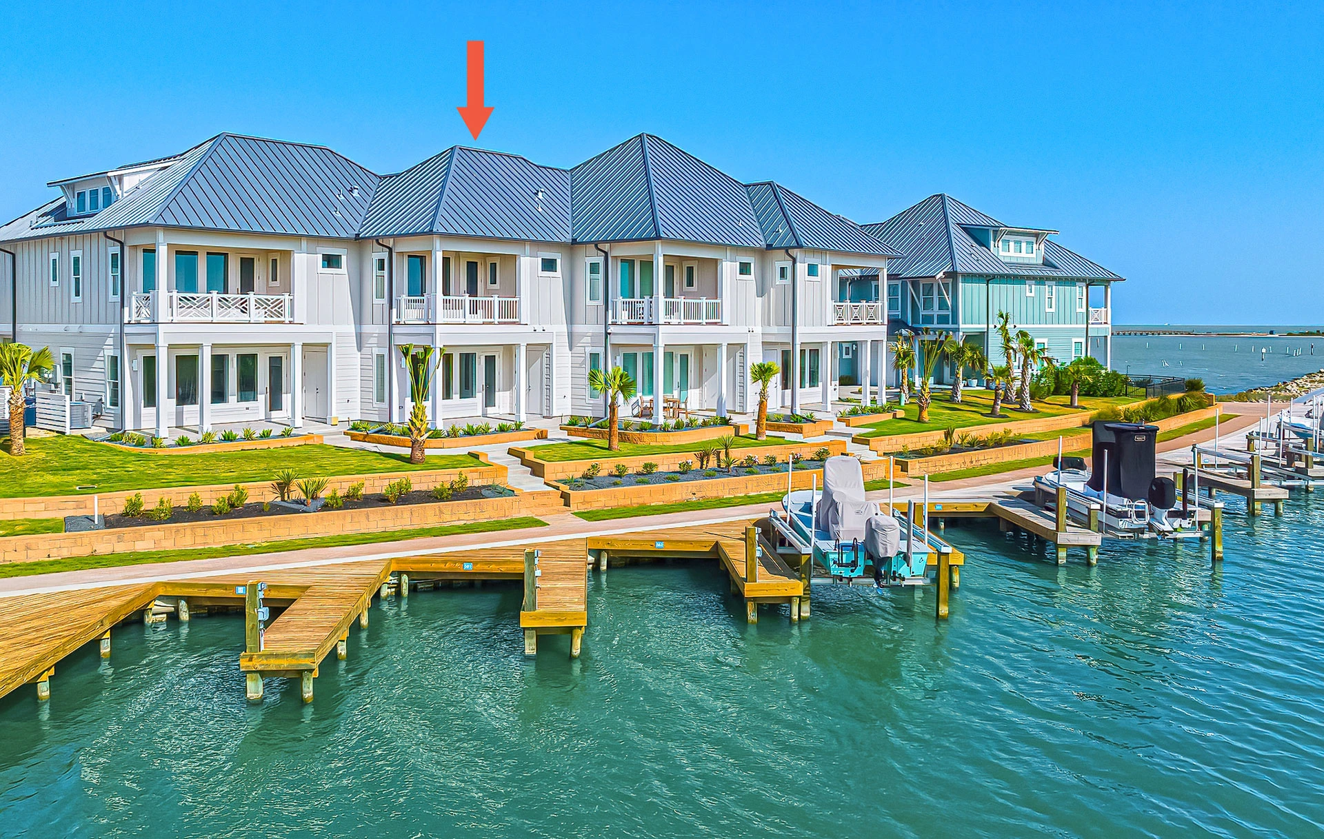 Coastal waterfront townhomes with boat docks and a red arrow pointing to one unit.